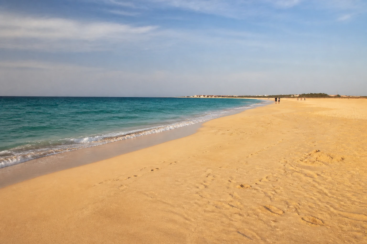 Plage de sable doré au Cap-Vert avec mer turquoise et voyageurs au loin